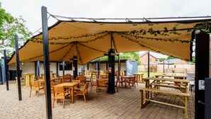 An outdoor seating area with wooden tables and chairs under a large canopy. - The Birley Arms Hotel (Preston)
