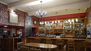 A bar with wooden furniture, a chandelier, and a wall clock. - The Birley Arms Hotel (Preston)