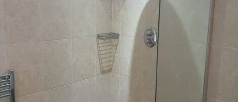 Eine Duschkabine mit Glaswänden, einer Handbrause, einer Glasduschtür und einem Metallhandtuchhalter.