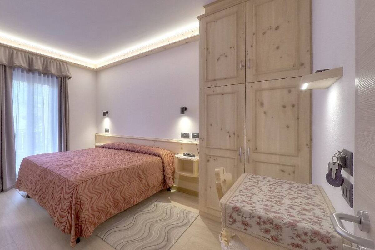 Ein Schlafzimmer mit Bett, Nachttisch, Kleiderschrank und einem Badezimmer mit Toilette und Waschbecken.