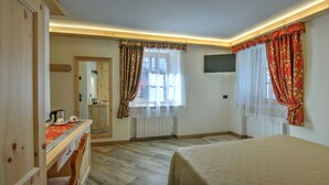 A hotel room with a bed, a desk with a kettle, a radiator, and a TV mounted on the wall. - Hotel Ristorante Federia (Livigno)