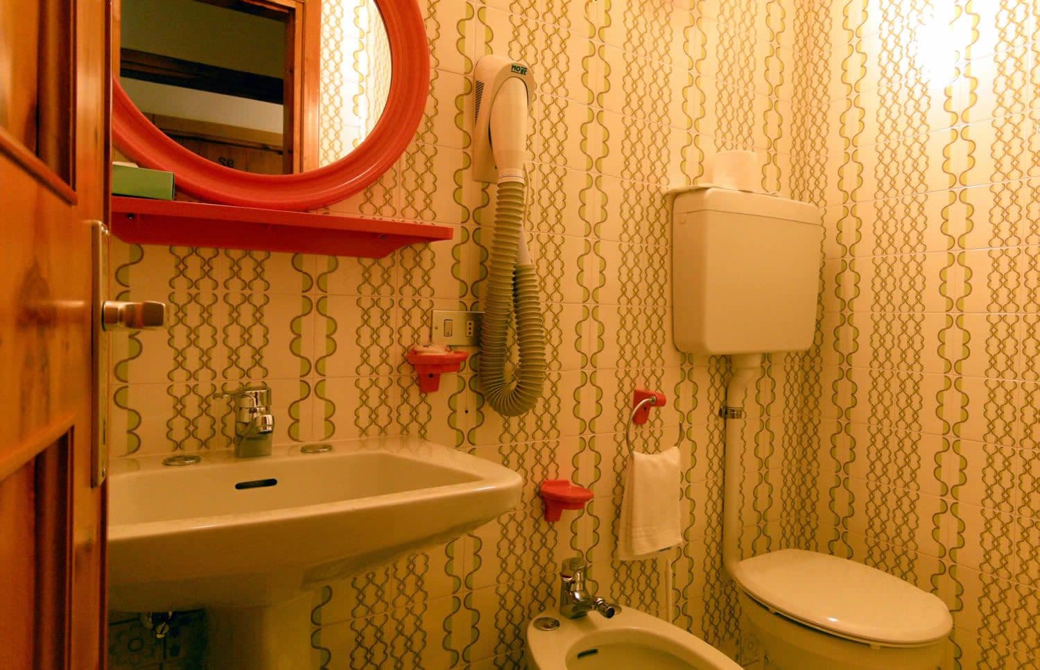 Baño con lavamanos, inodoro y secador de pelo montado en la pared.