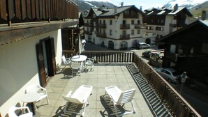 A terrace with outdoor seating, a view of mountain buildings, and a snow-capped mountain in the background. - Hotel Ristorante Federia (Livigno)