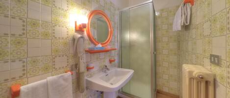 Un baño con lavamanos, espejo, toallero, ducha y radiador.