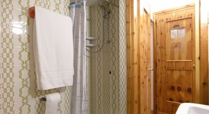 A bathroom with a shower, a wooden door, and patterned tiles. - Hotel Ristorante Federia (Livigno)