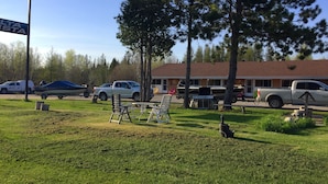 A motel with a signboard, outdoor seating, and parked vehicles. - Alta Vista Motel (Baldwin)