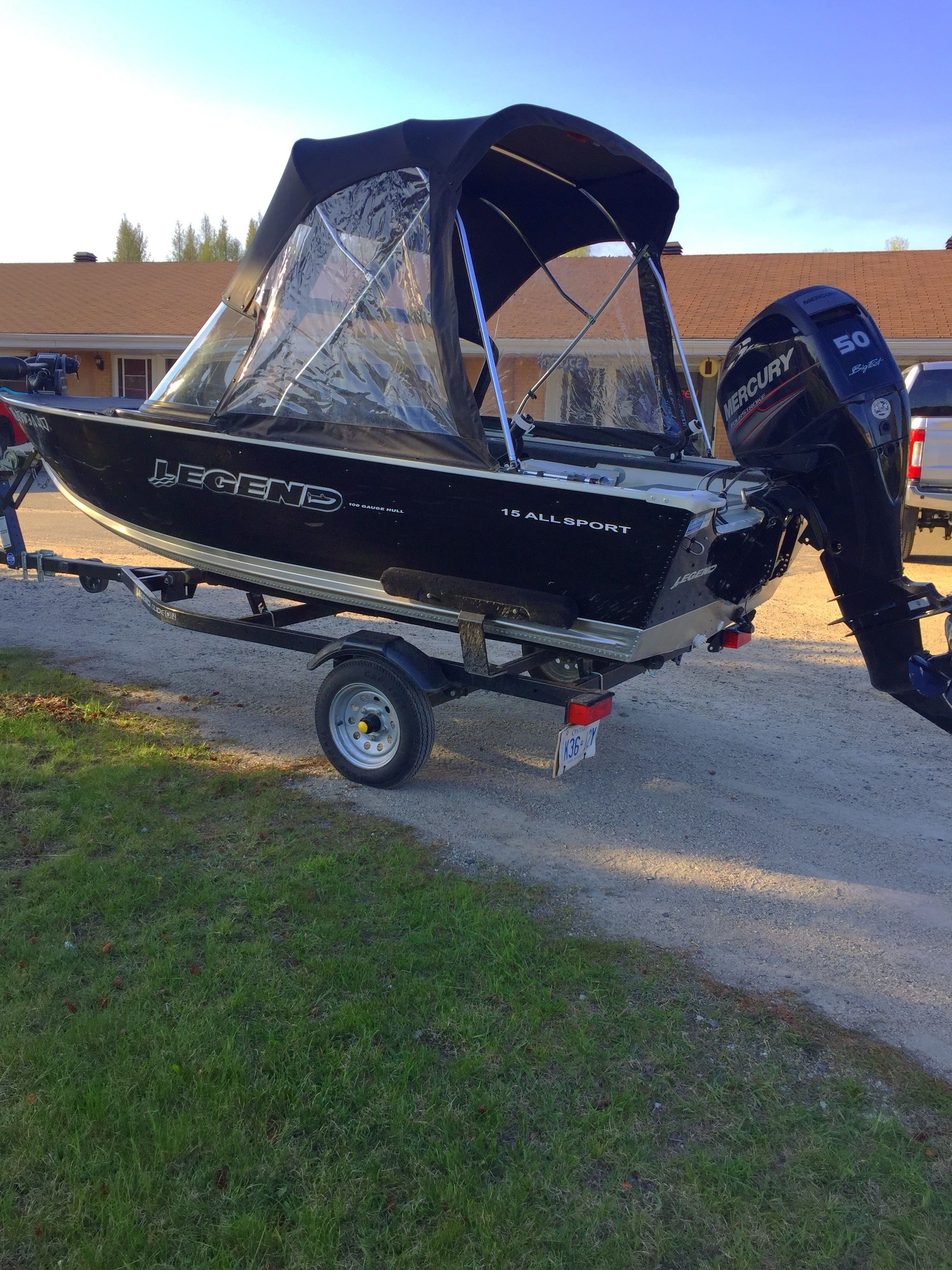 A black boat with a canopy, labeled "Legend 15 All Sport," on a trailer.