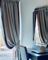 A room with a desk, a chair, a mirror, and curtains.