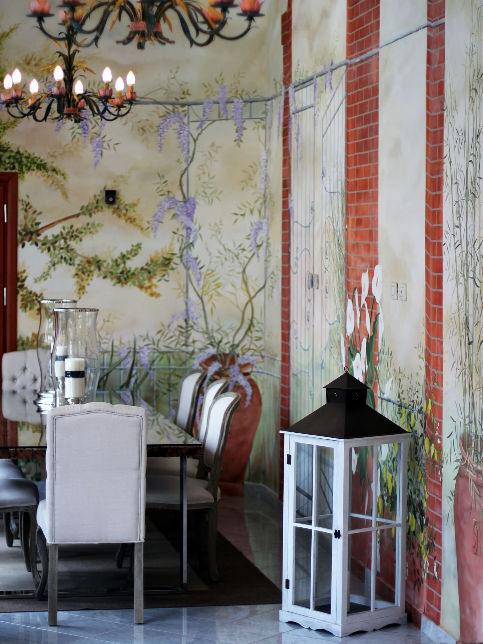A dining area with a table set for two, a chandelier, and a decorative lantern.