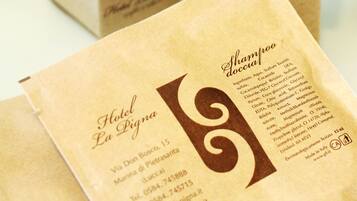 Hotel La Pigna's branded stationery items, including a business card and a small box, with contact information and a list of ingredients for their shampoo.