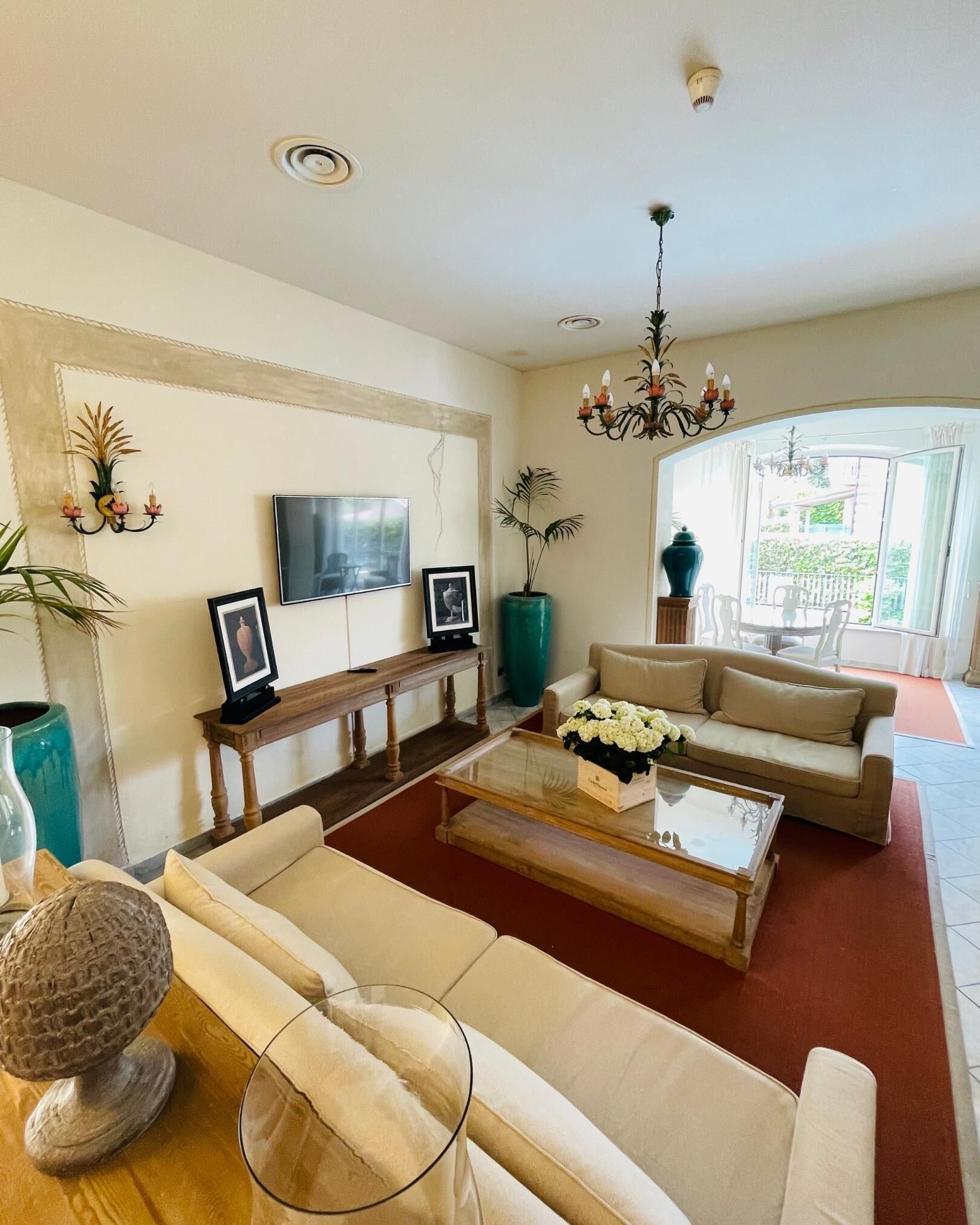 A living room with a sofa set, a coffee table, a TV, and a chandelier.