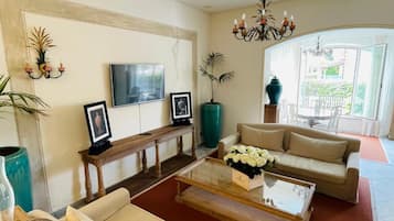 A living room with a sofa set, a coffee table, a TV, and a chandelier.