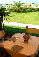 Mesa colocada al aire libre con vista a una playa y palmeras.