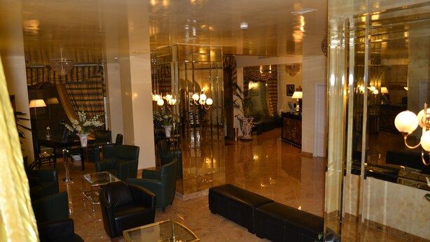 A spacious lobby with leather sofas, a glass coffee table, and a chandelier. - Hotel Europa (Rho)