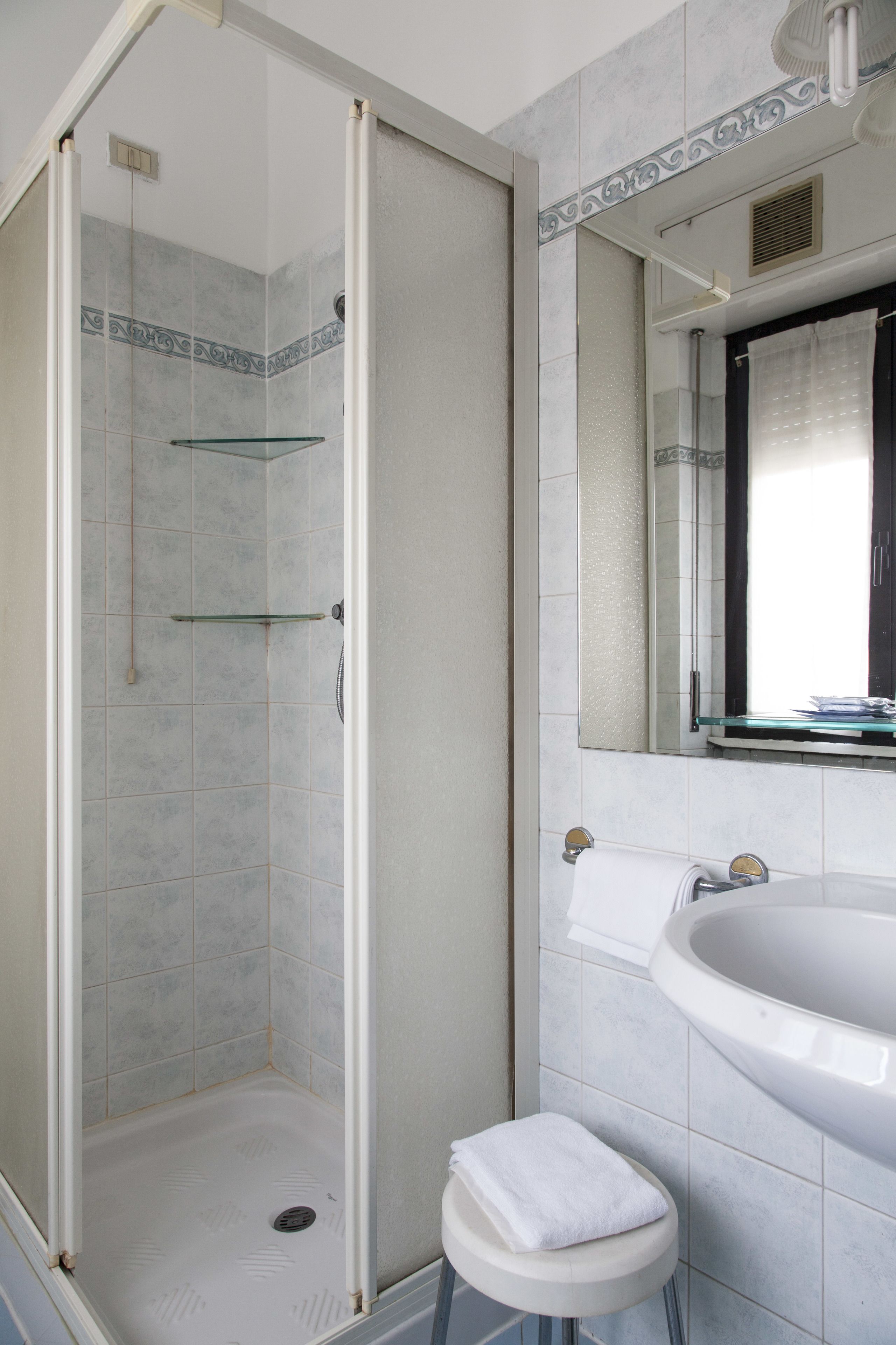 A bathroom with a glass-enclosed shower, a white sink, and a mirror above the sink.
