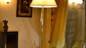A room with a standing lamp, a framed picture on the wall, a potted plant, and a glass table. - Hotel Europa (Rho)
