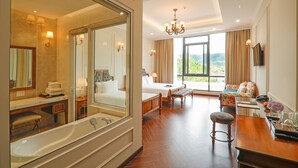 Una habitación amplia con una cama grande, una zona de estar con vistas y un baño separado con bañera.
