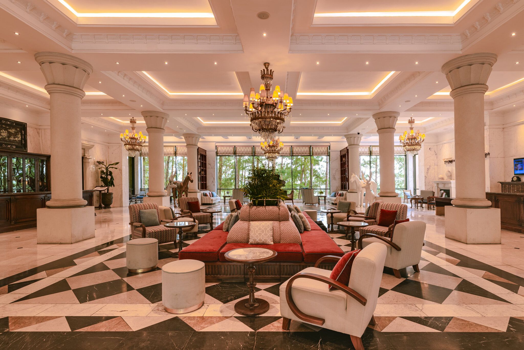 A spacious lobby with a checkered floor, a central seating area, and a chandelier.