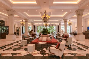 A spacious lobby with a checkered floor, a central seating area, and a chandelier.
