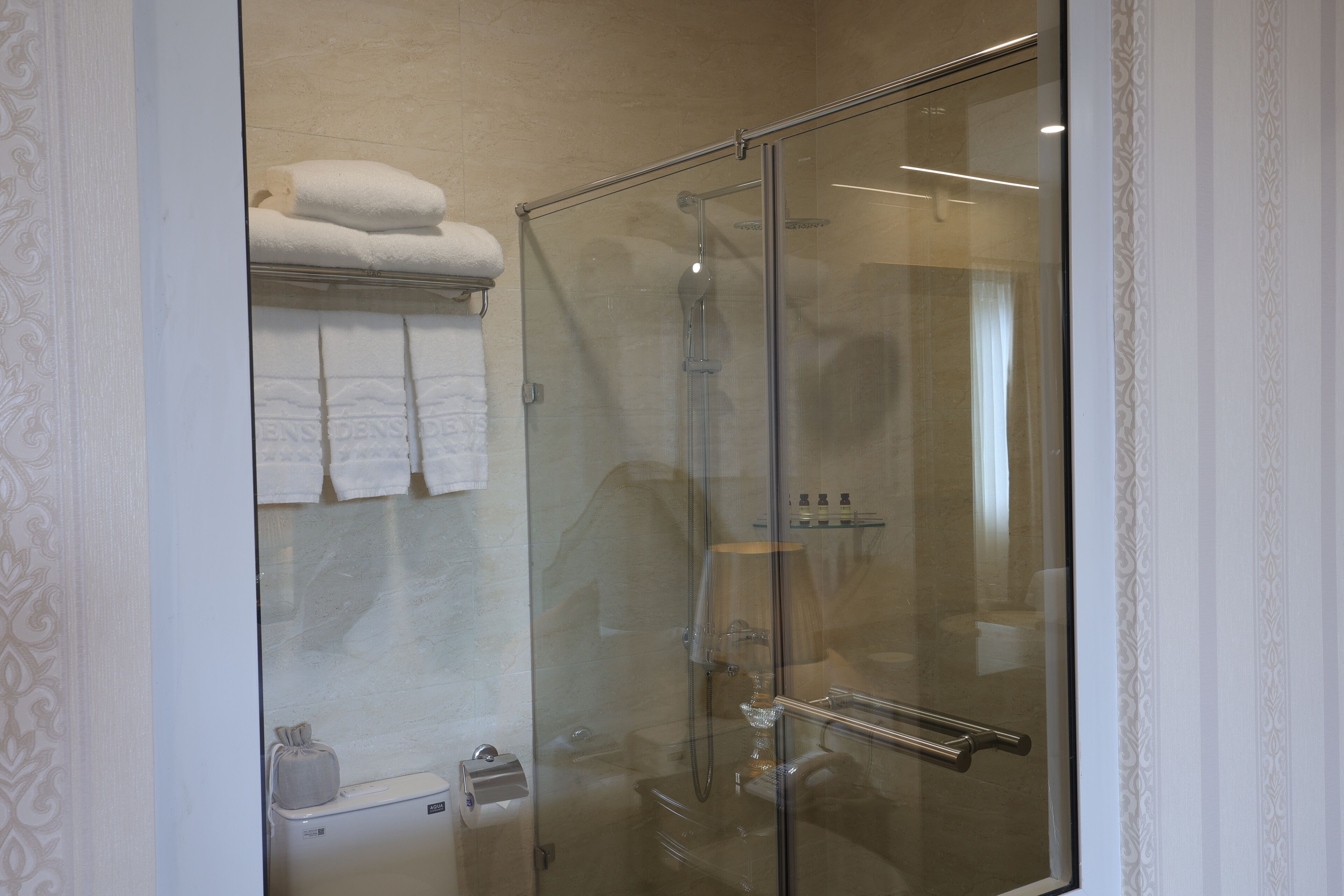 A glass-enclosed shower with a towel rack above it.