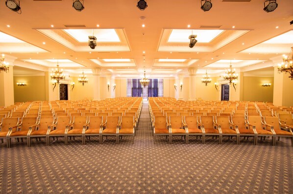 A large, well-lit conference room with rows of chairs and a patterned carpet.