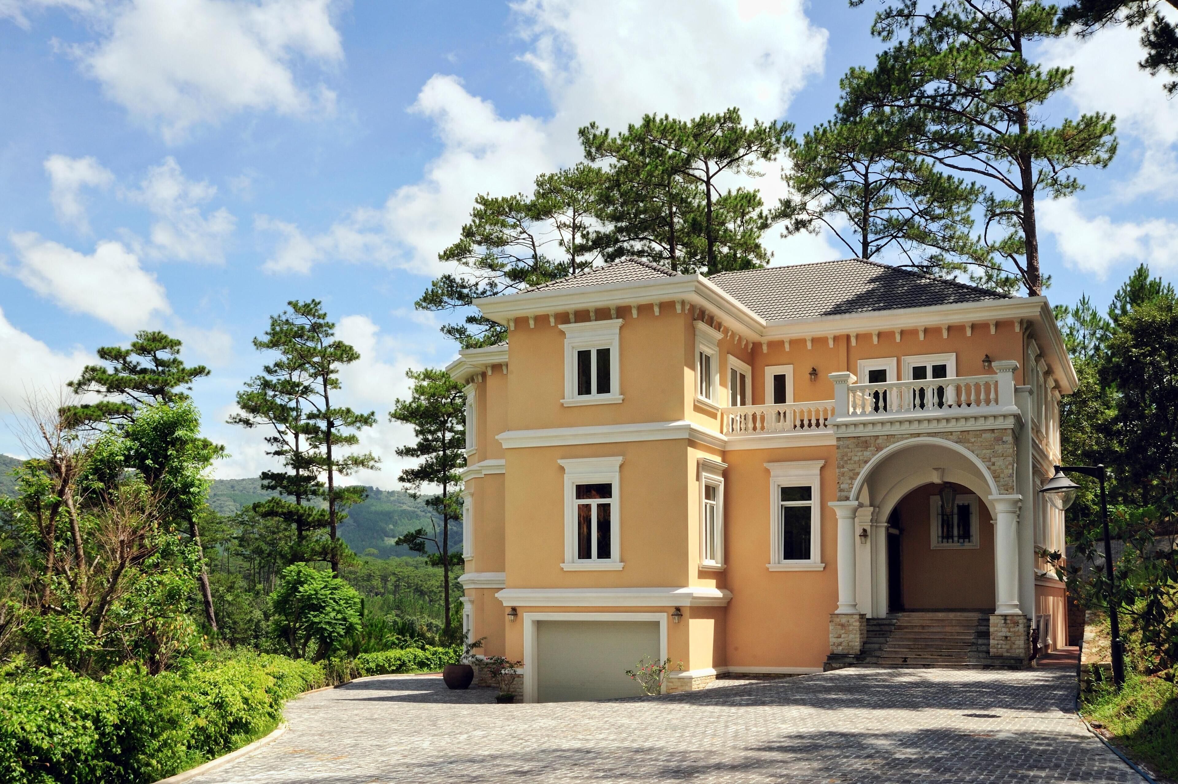 A two-story house with a balcony, a garage, and a driveway leading to the entrance.