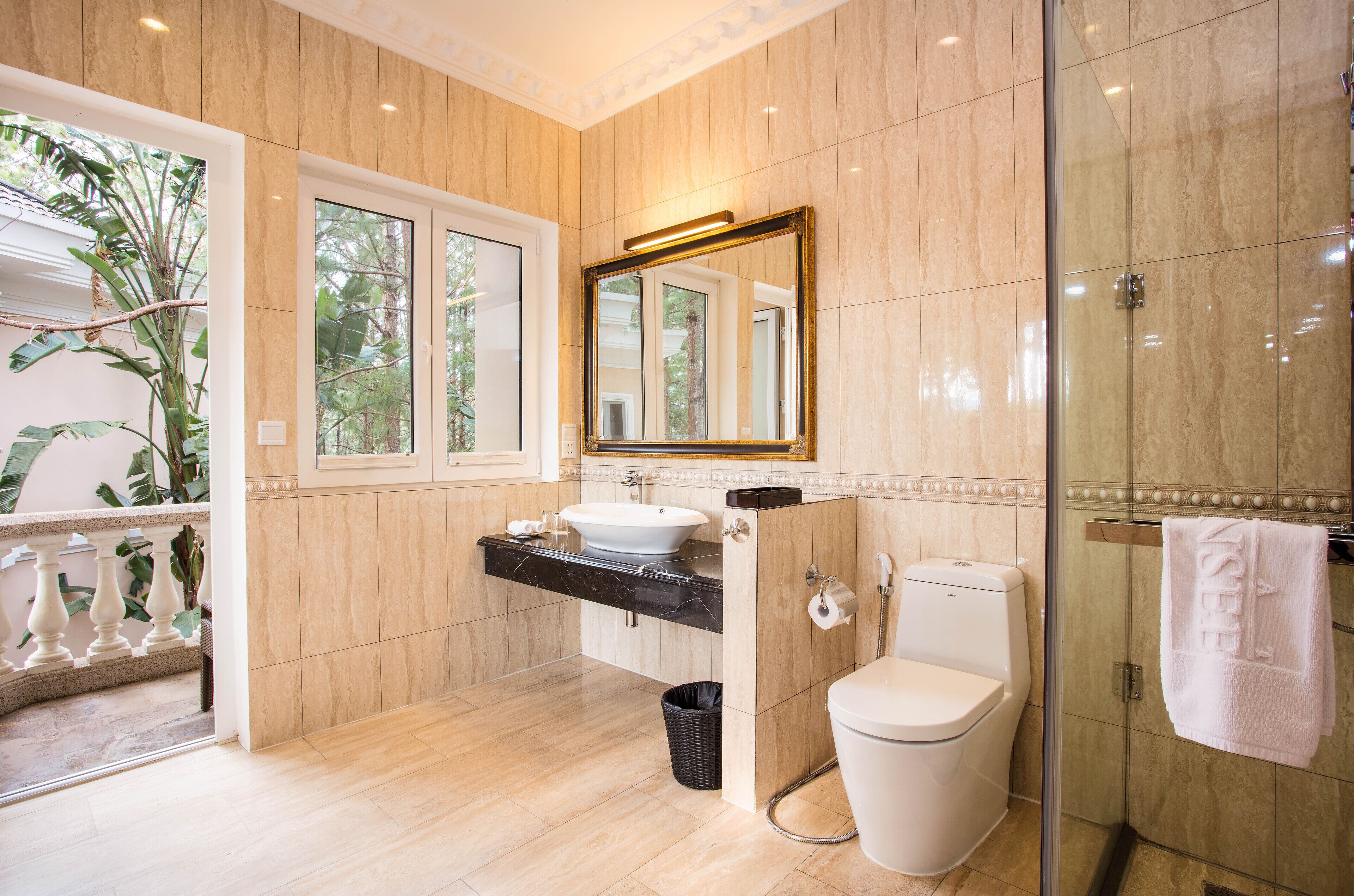 A modern bathroom with a glass shower, a white toilet, a sink with a black countertop, and a large mirror.