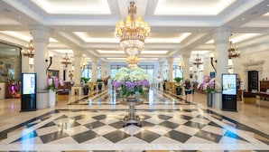 A spacious lobby with a checkered floor, a grand chandelier, and multiple flower arrangements. - Dalat Edensee Lake Resort & Spa (Xuan Huong - Da Lat)