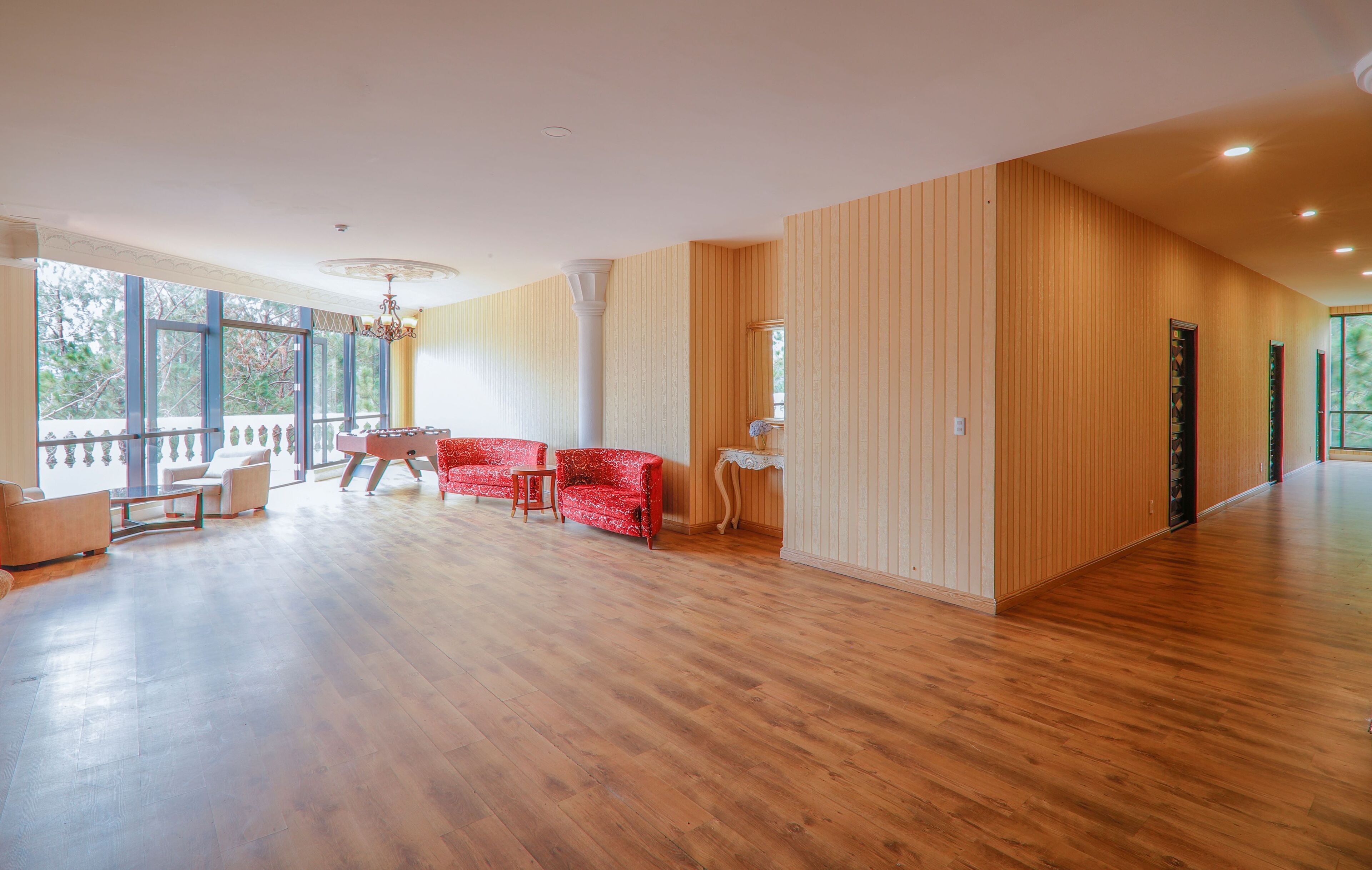 Una habitación amplia con suelo de madera, un sofá rojo y una mesita.