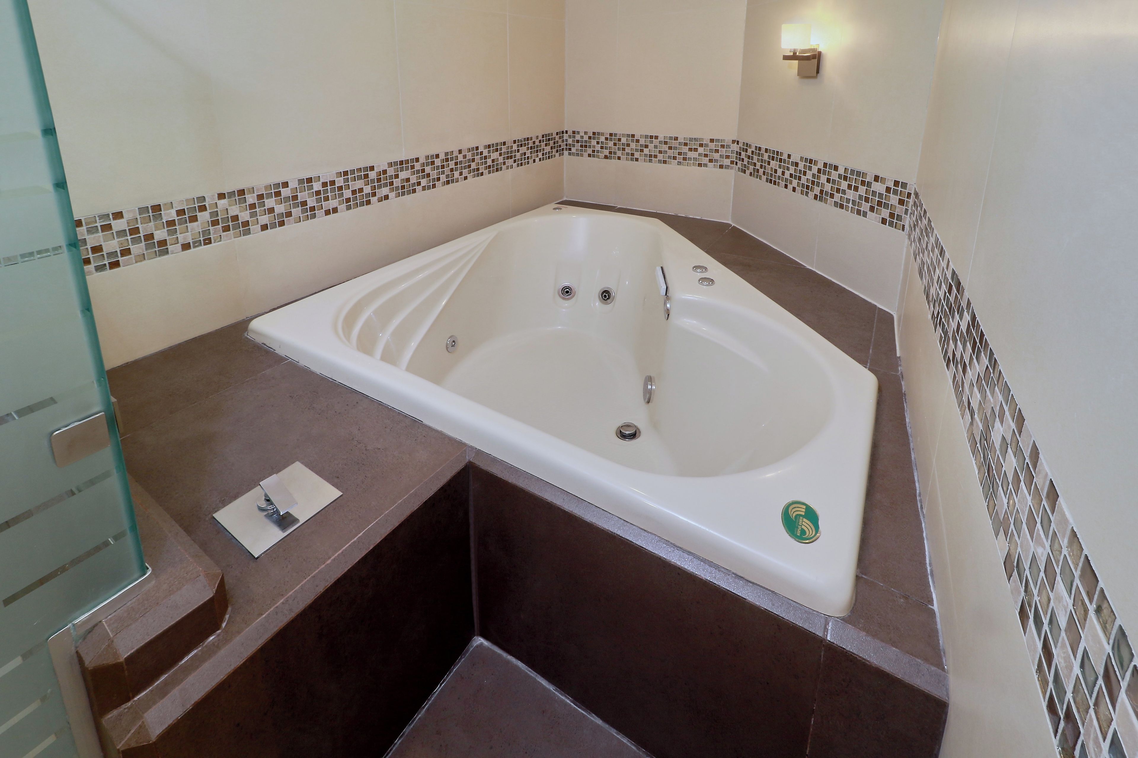 Un baño con una bañera grande, un lavamanos pequeño y una cabina de ducha con mampara de vidrio.