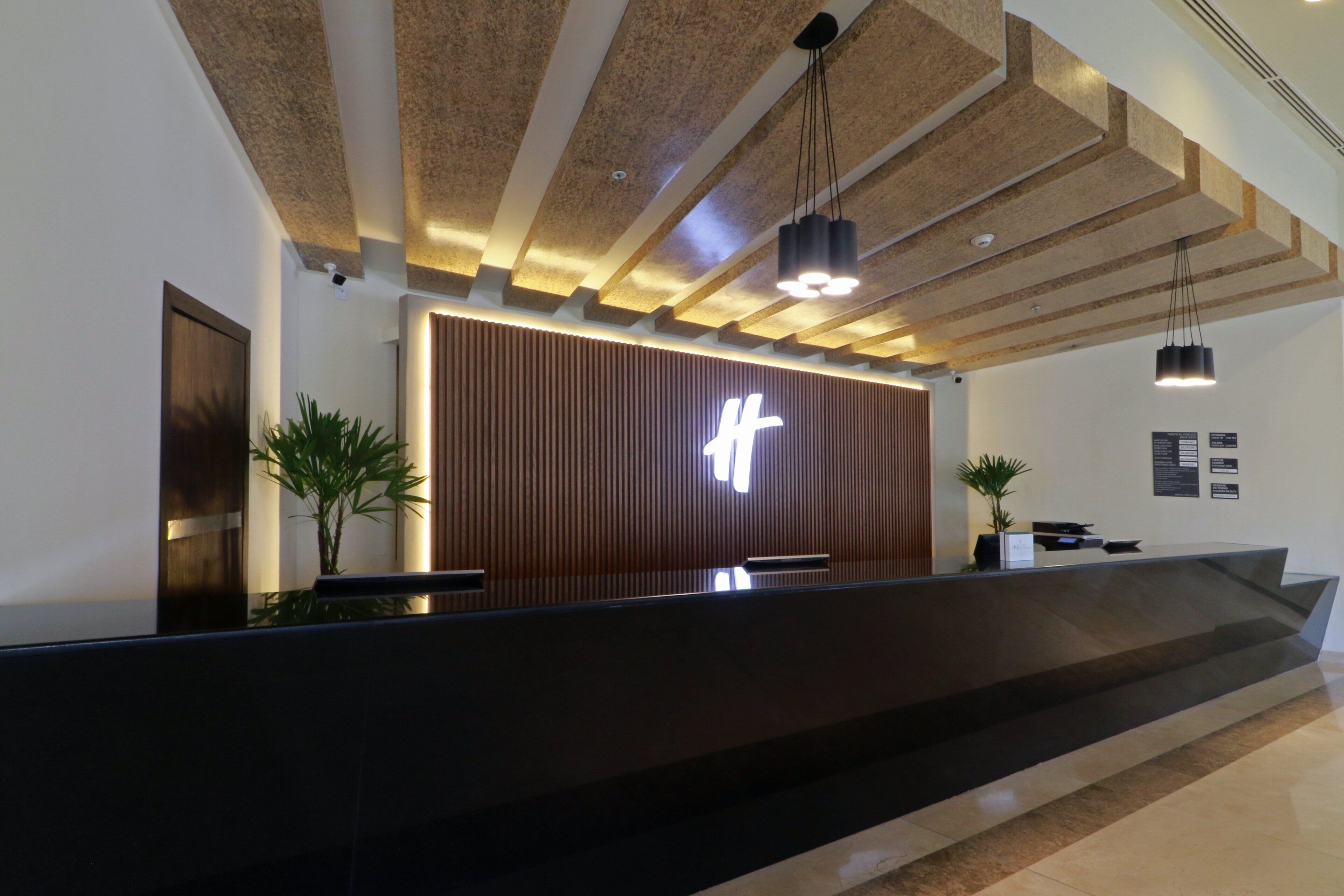 A reception desk with a modern design, featuring a wooden panel wall and a prominent illuminated sign.