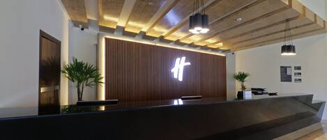 A reception desk with a modern design, featuring a wooden panel wall and a prominent illuminated sign.