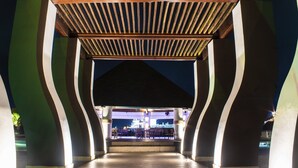 A covered outdoor area with a central open space, possibly a patio or courtyard, surrounded by columns and a sloped roof structure.