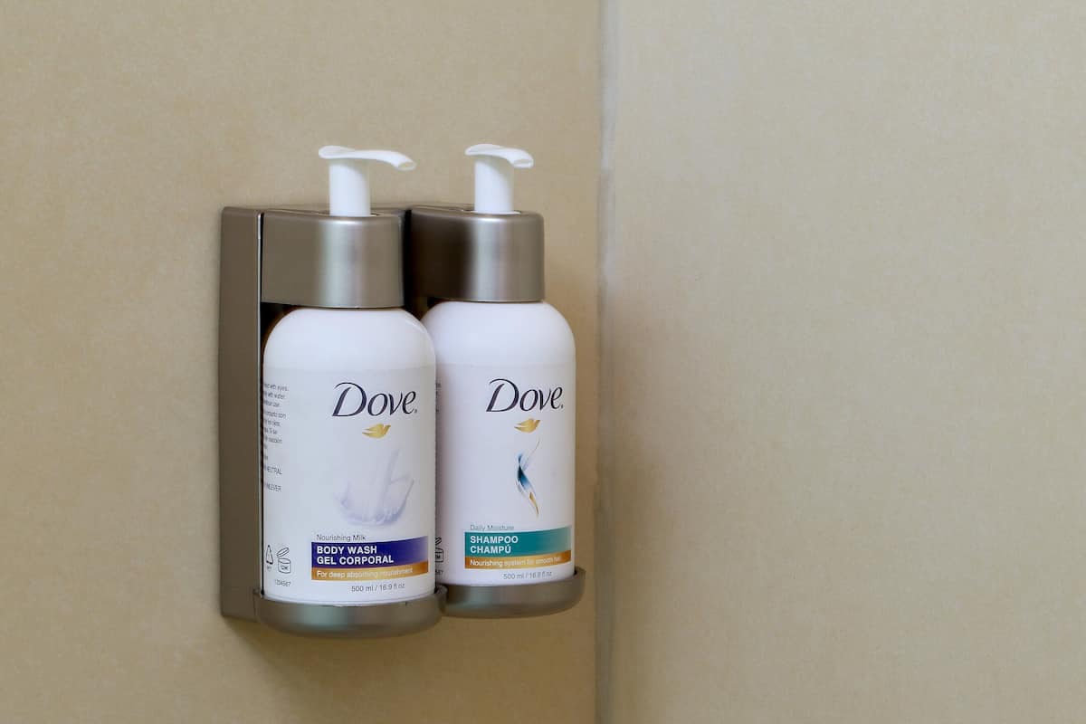 Dos botellas de gel de ducha y champú Dove colgadas en una pared.