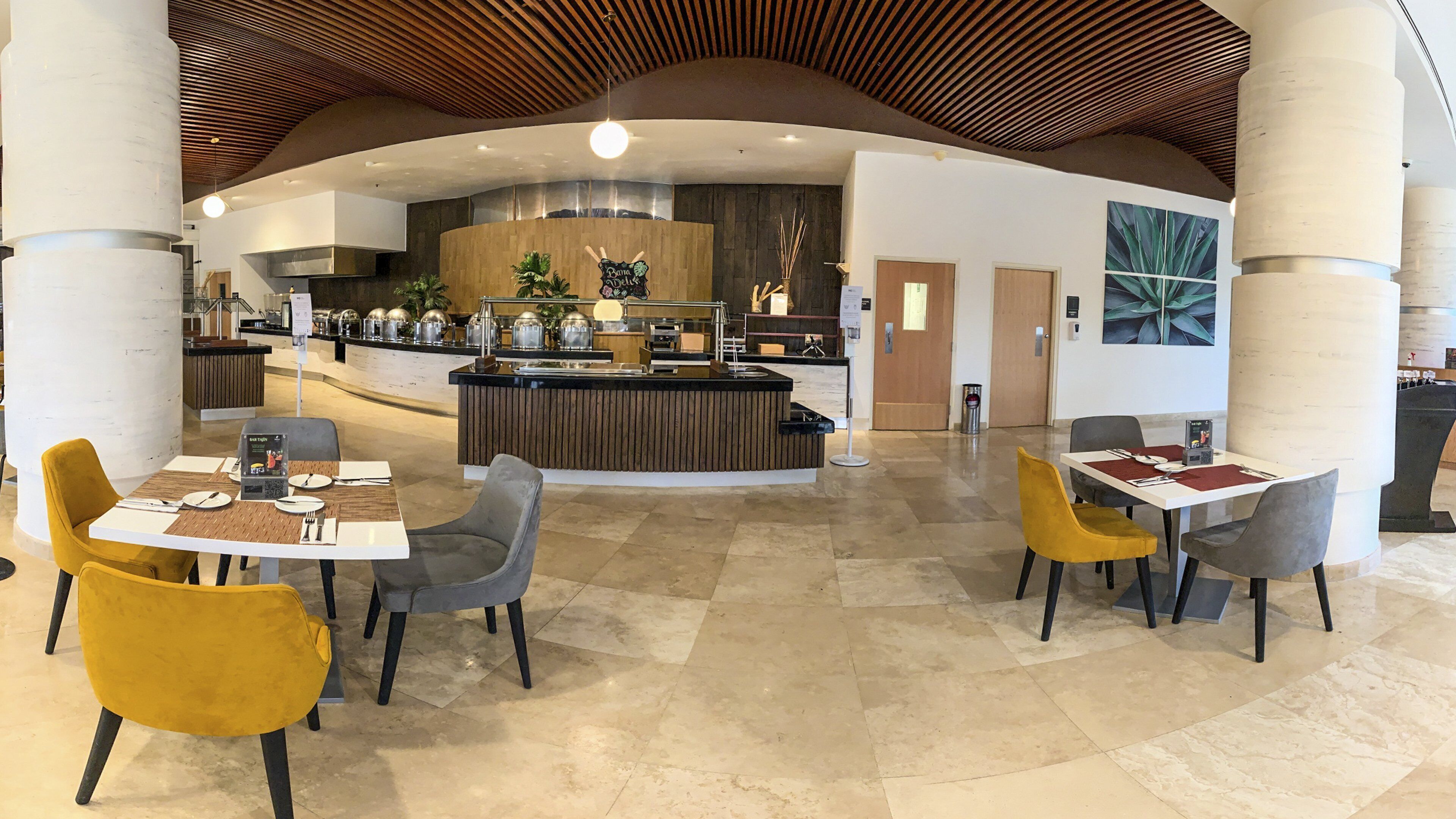 A modern hotel lobby with a central bar area, seating arrangements, and a reception desk.