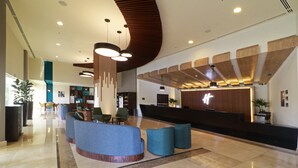 A modern lobby with a reception desk, seating area, and a large plant.