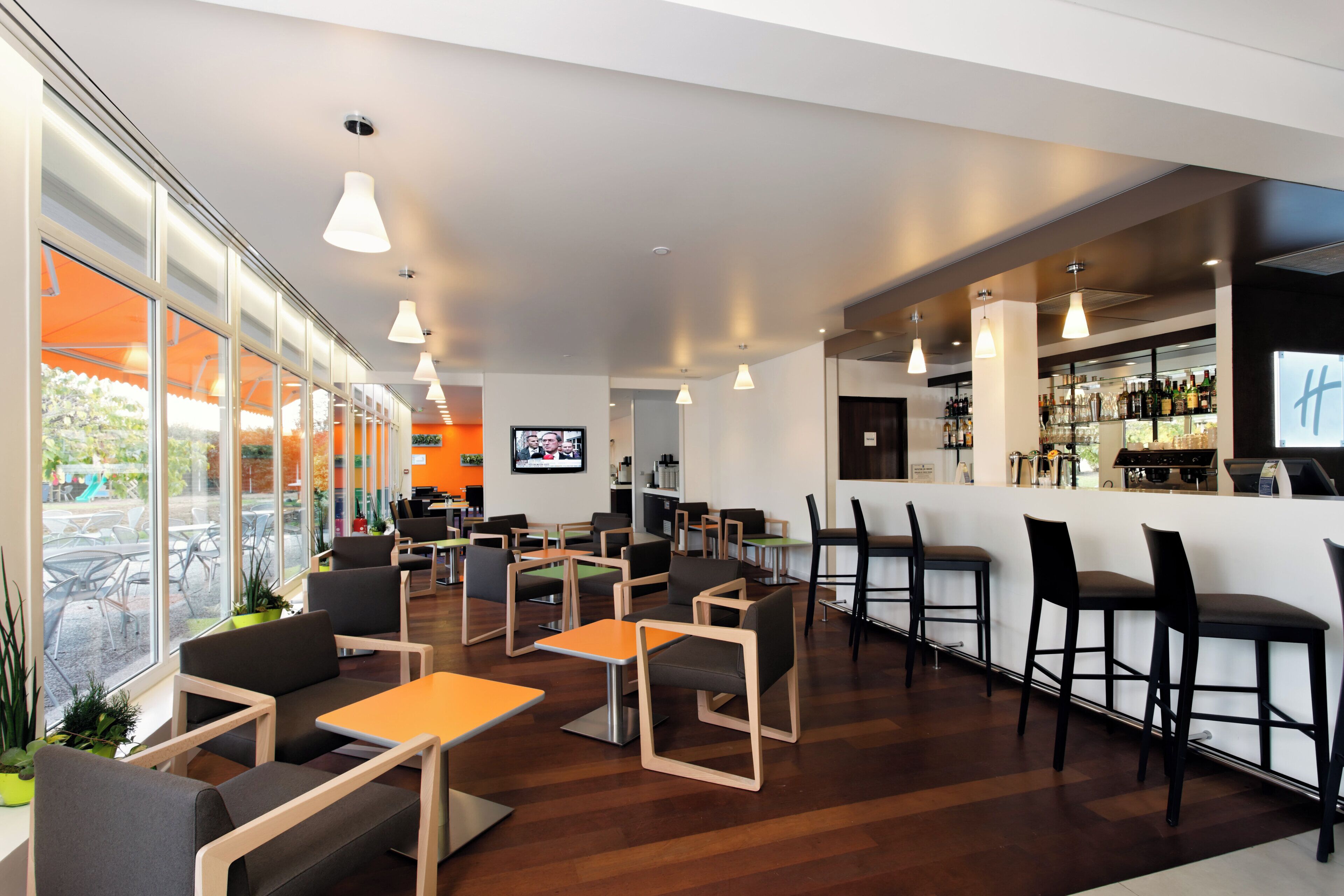 A modern bar area with seating, a television, and a bar counter with various bottles.