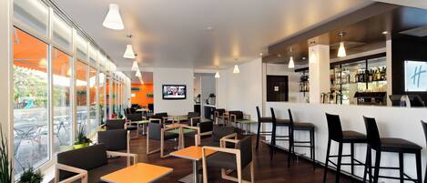 Un área de bar moderna con asientos, un televisor y una barra con diversas botellas.