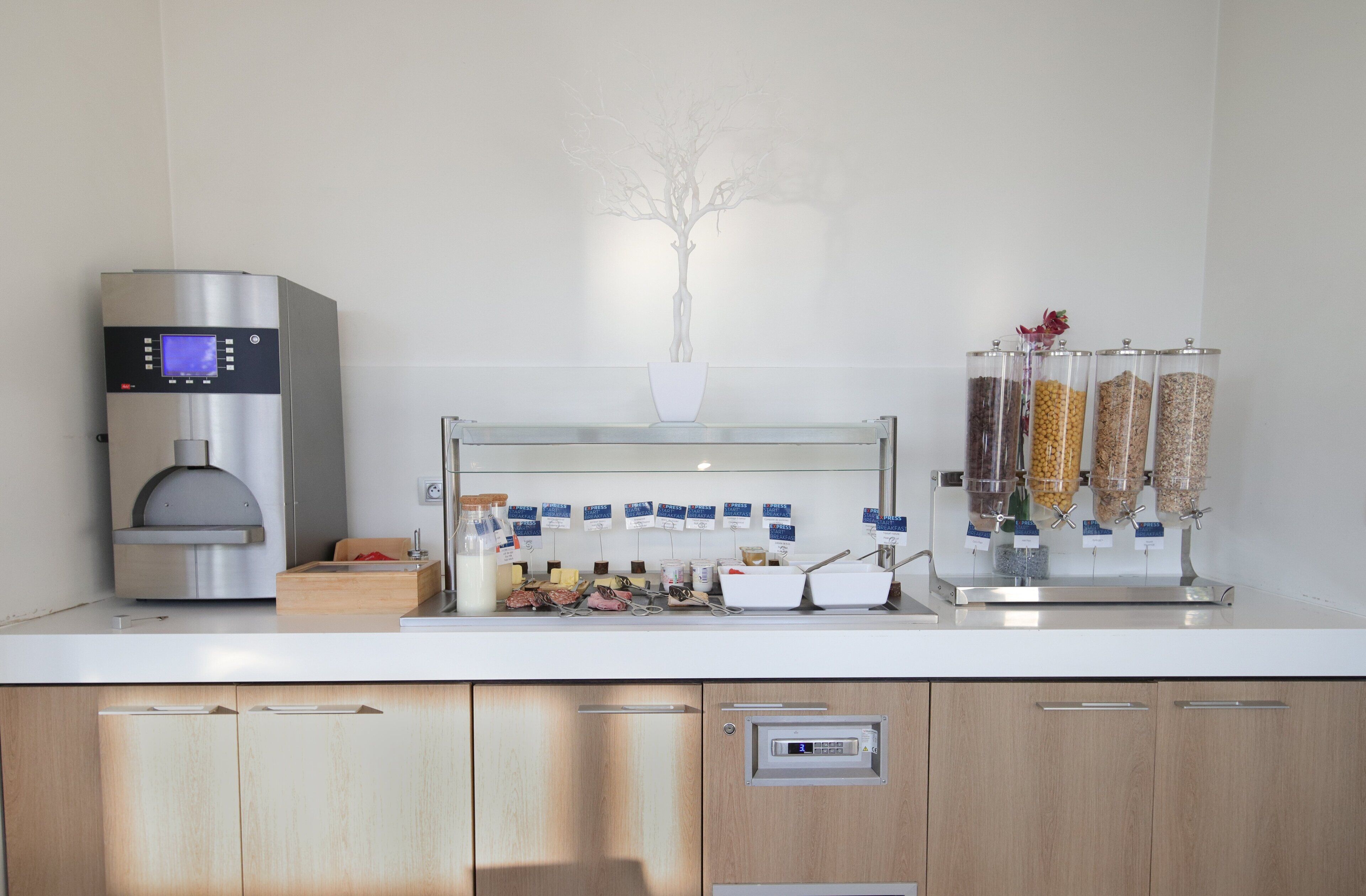 Une cuisine moderne équipée d’une machine à expresso intégrée, d’un espace dédié au café, ainsi que d’une variété de condiments et d’en-cas.