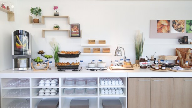 A buffet setup with various food items, serving trays, and storage shelves. - Holiday Inn Express Strasbourg - Sud by IHG (Geispolsheim)