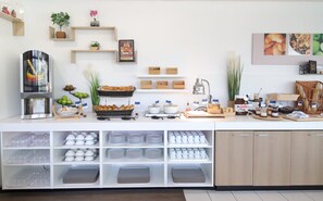 A buffet setup with various food items, serving trays, and storage shelves. - Holiday Inn Express Strasbourg - Sud by IHG (Geispolsheim)