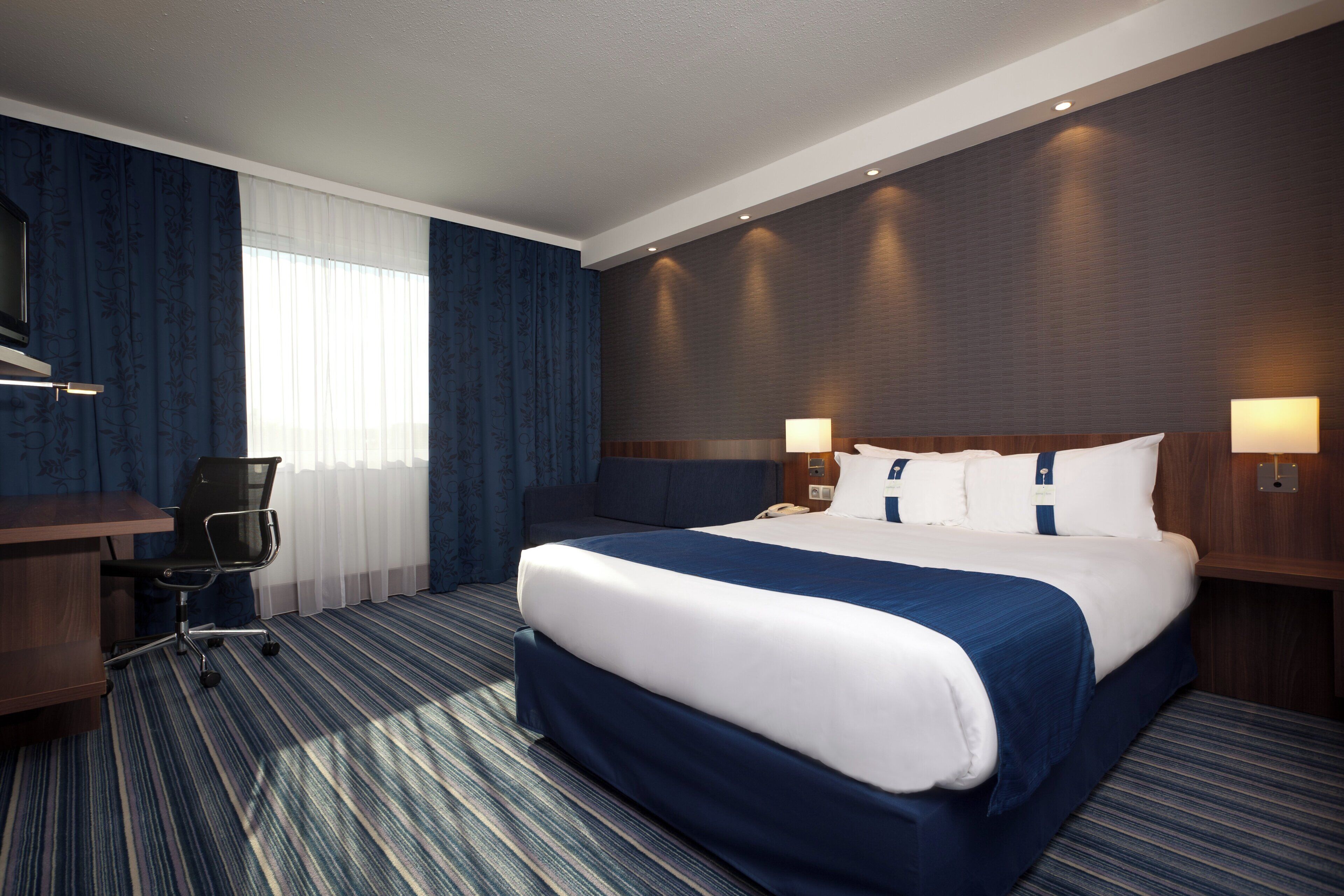 Una habitación de hotel con una cama grande, un escritorio, una silla y un teléfono.