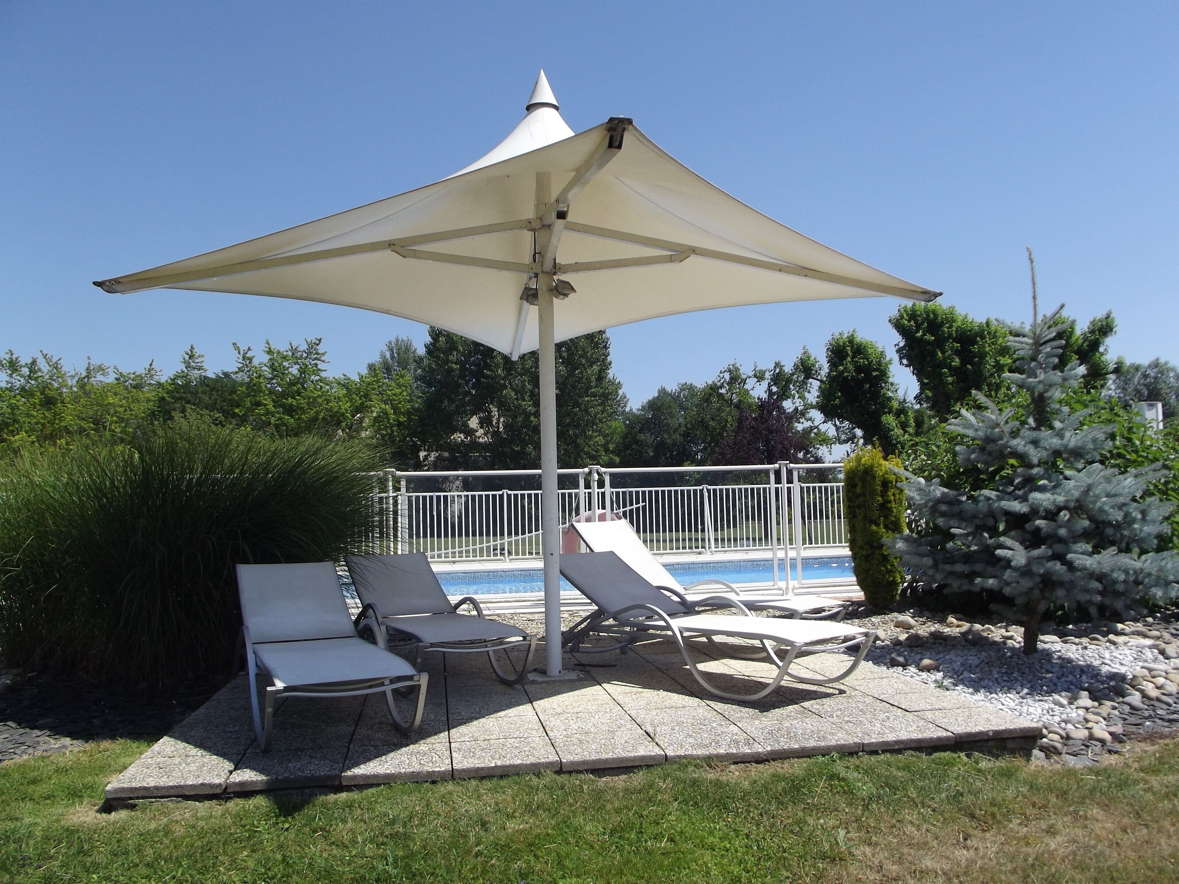 A poolside area with lounge chairs and a large umbrella.