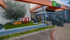 A modern hotel entrance with a 'Welcome' sign, a large heart-shaped decoration, and a 'Hertz Express' sign above. - Holiday Inn Express Strasbourg - Sud by IHG (Geispolsheim)