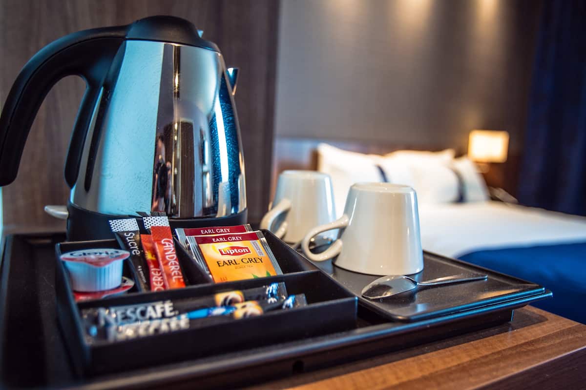 A tray with a coffee maker, two mugs, and a selection of coffee pods including Earl Grey and Lipton.