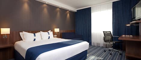 A hotel room with a large bed, a desk, and a chair.