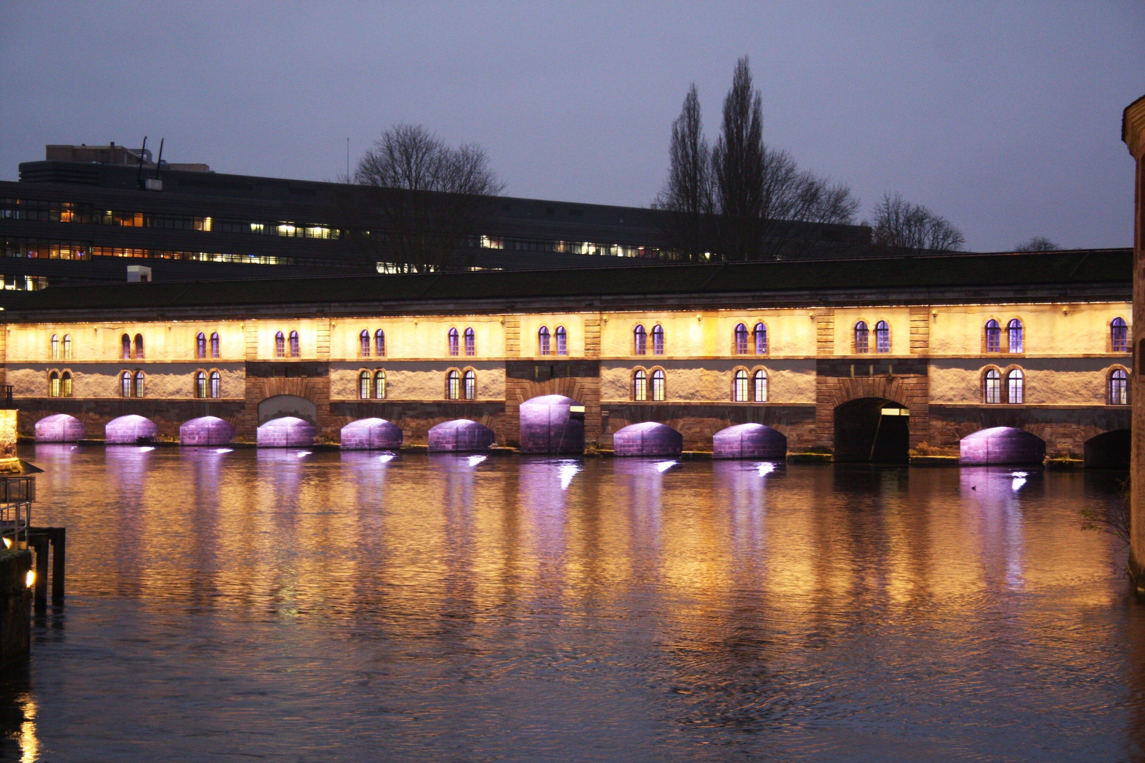 A building with multiple arched windows and a water body in front.