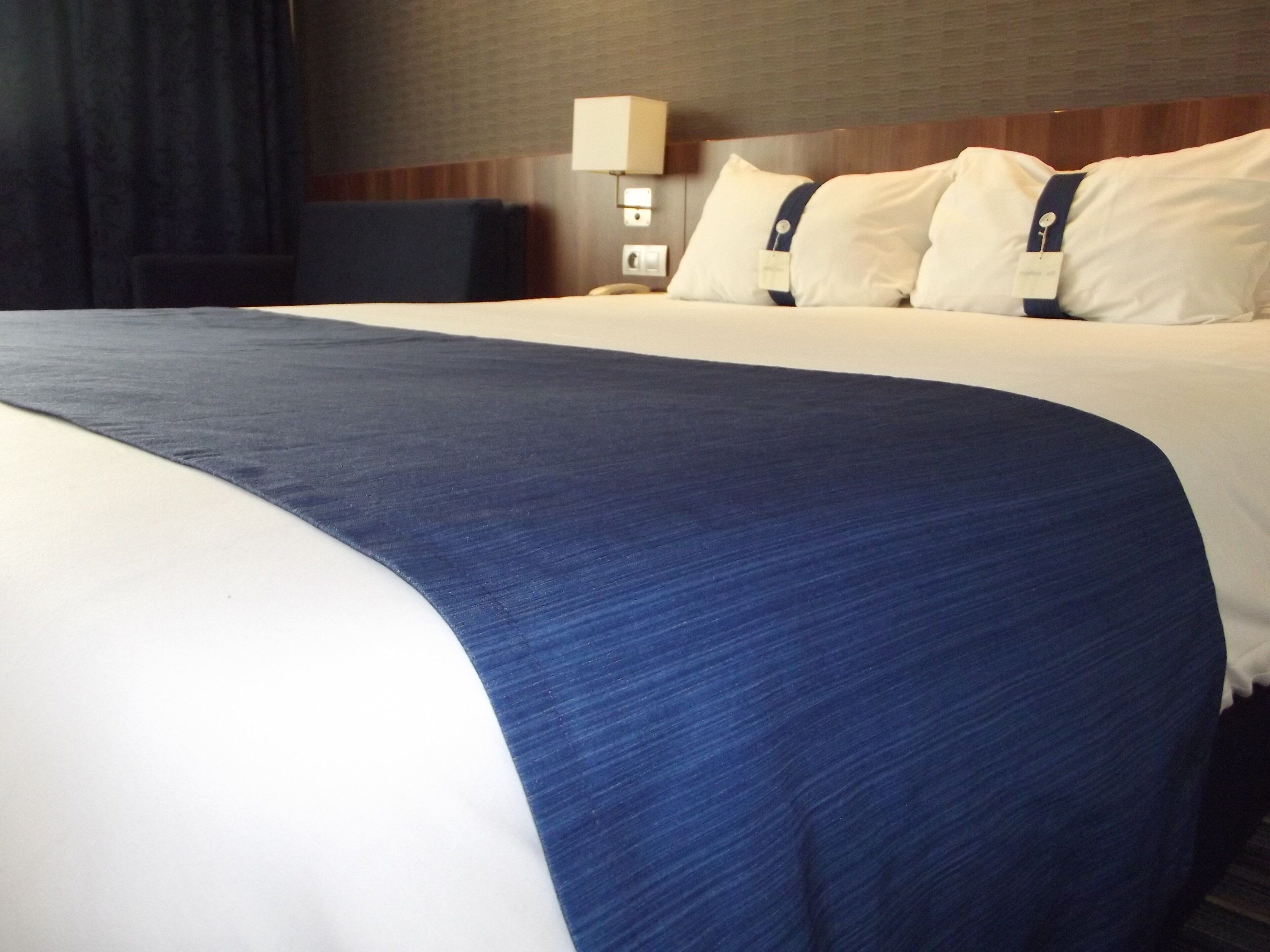 A hotel room with a large bed, a bedside lamp, and a headboard.