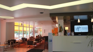 A modern hotel lobby with a reception desk, seating area, and large windows. - Holiday Inn Express Strasbourg - Sud by IHG (Geispolsheim)