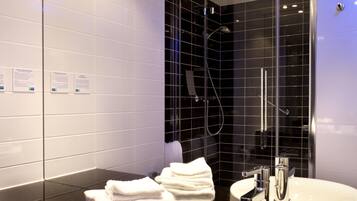 A modern bathroom with two sinks, a glass shower enclosure, and a mirror.